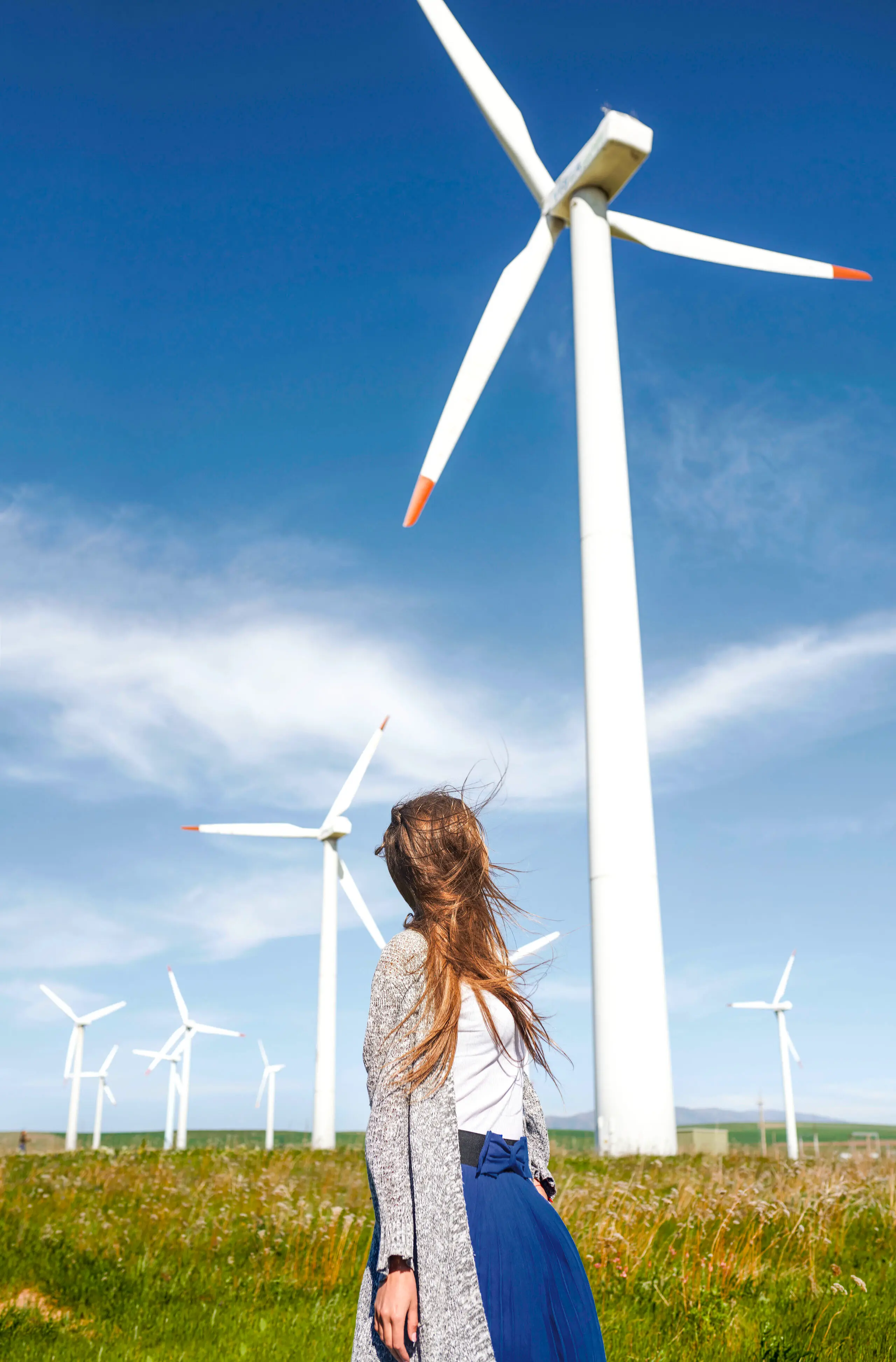 Frau steht vor Windkraftanlage